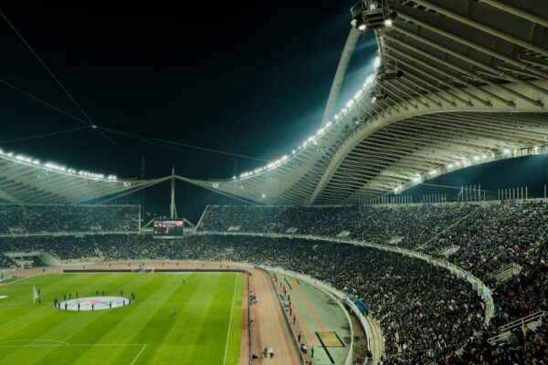 Een vol voetbalstadion van bovenaf gezien tijdens een avondwedstrijd