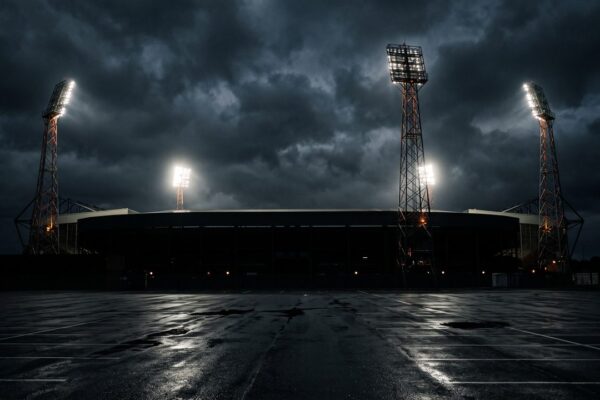De verlichte lichtmasten van een voetbalstadion tegen een donkere avondlucht, sfeerbeeld bij het FC Utrecht programma