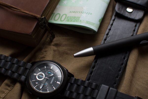Horloge, eurobiljetten en een pen op een donkere achtergrond, symbool voor een verdiend en verspeeld voetbalfortuin