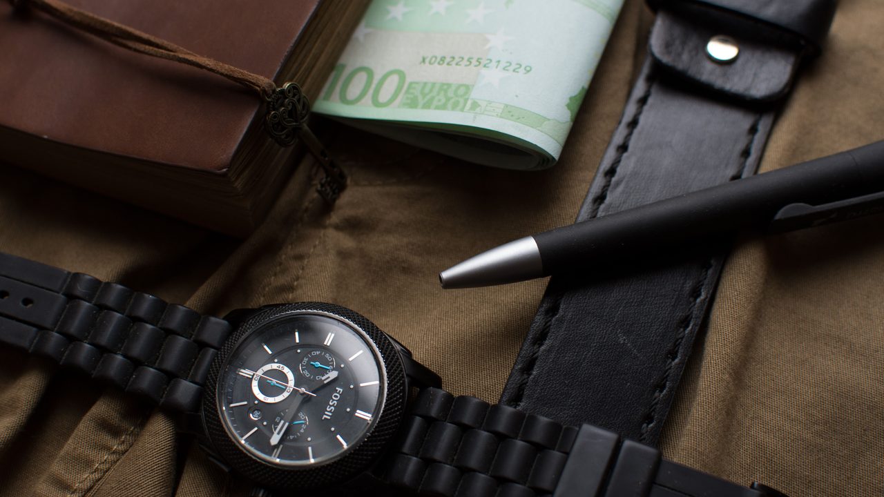 Horloge, eurobiljetten en een pen op een donkere achtergrond, symbool voor een verdiend en verspeeld voetbalfortuin