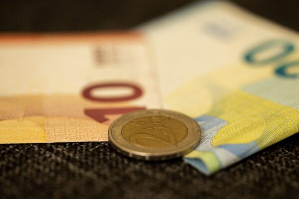 Eurobiljetten en een muntstuk van twee euro op een donkere ondergrond, symbool voor het onbekende fortuin van een assistent-trainer