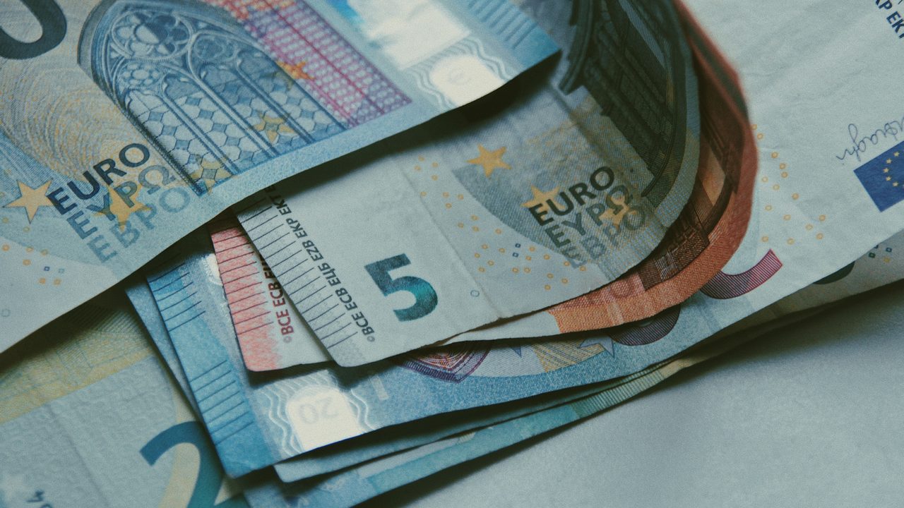 Uitgewaaierde eurobiljetten in gedempt licht, symbool voor het fortuin van een oud-voetballer