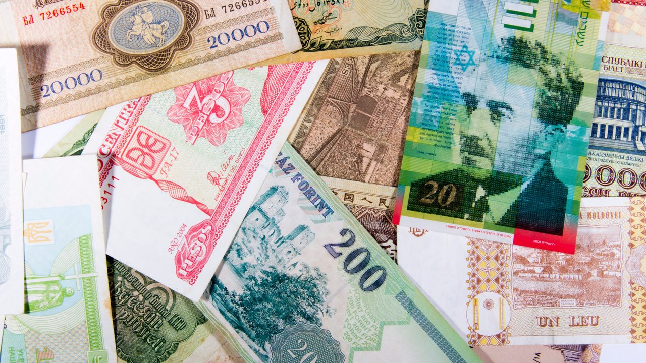 Bankbiljetten uit verschillende landen naast elkaar, symbool voor een verdiend en verspeeld wereldfortuin