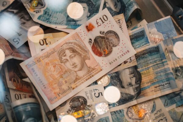 Britse pond-bankbiljetten en munten op een donkere achtergrond, symbool voor de verdiensten van een keeper in Engeland