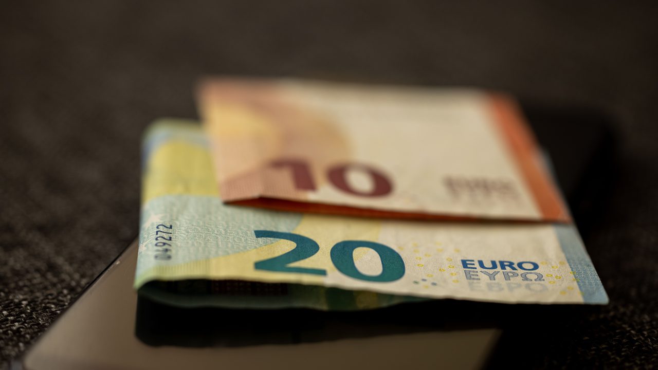 Eurobiljetten op een smartphone, symbool voor de verdiensten van een tv- en radiopresentator
