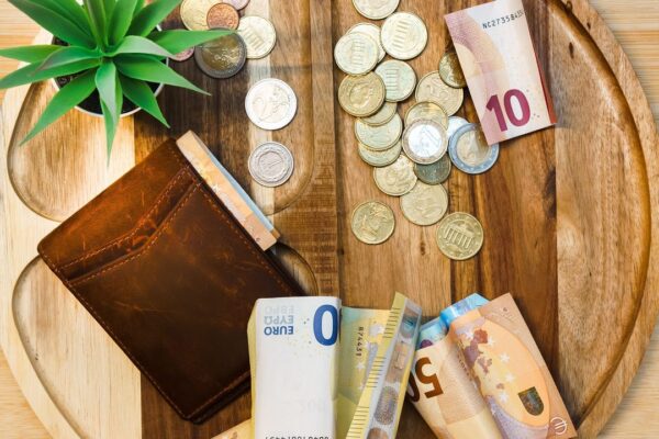Eurobiljetten en munten op een houten dienblad, symbool voor de verdiensten van een oud-topspits